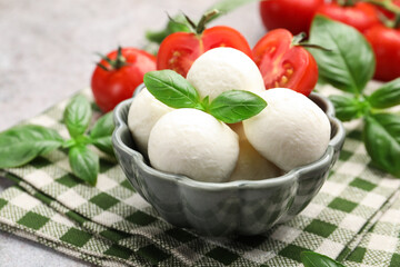 Tasty mozzarella cheese balls, tomatoes and basil on table, closeup