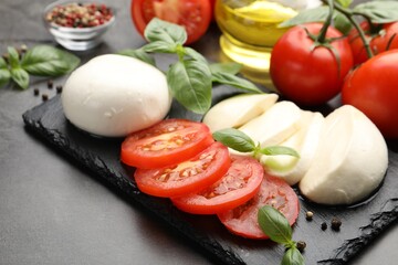 Tasty mozzarella cheese, tomatoes, basil and spices on grey table, closeup