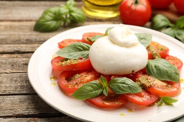 Tasty salad Caprese served with pesto sauce on wooden table, closeup