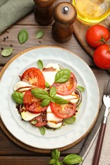 Tasty salad Caprese served with balsamic vinegar on wooden table, flat lay