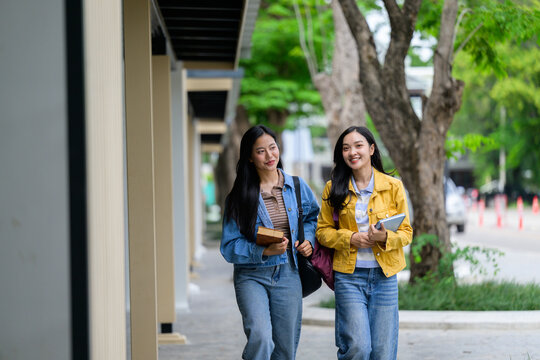 Two happy female students walking and talking on campus