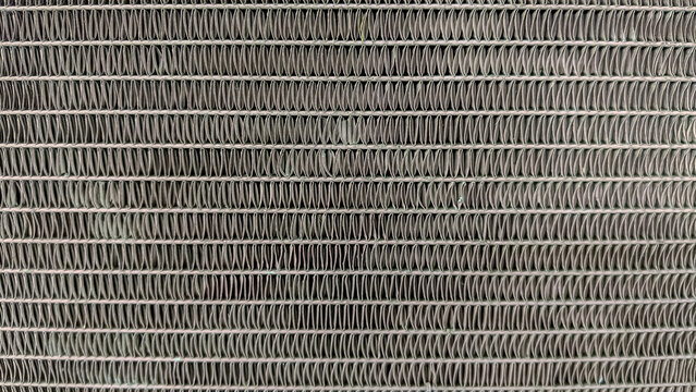 Abstract metal texture background of tightly packed air conditioner fins, creating a repetitive and symmetrical industrial pattern.