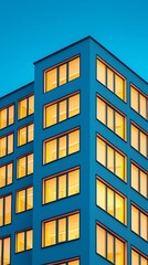 Minimalist Business Tower with Glowing Windows Against Evening Sky for Architectural Mockups, Warmly Lit Corporate Building at Dusk with Clear Blue Sky, contemporary architecture and urban lifestyle.