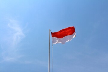 indonesia flag with red and white color on blue sky background. Indoonesia nation flag from textile material. Waving indonesian flag when ceremony independence day