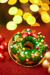 Christmas donut decorated like a christmas wreath with blurred lights in background