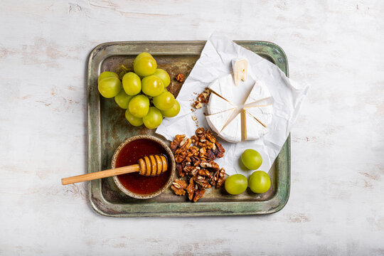 A colorful cheese platter with honey, sweet grapes, and crunchy walnuts, perfect for any gathering or celebration, appetizer for wine, snack board top view