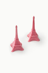 Two pink eiffel tower statues resting on white background
