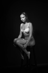 Slim young beautiful woman in lingerie full length low key black and white portrait