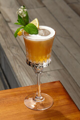 Whiskey sour cocktail decorated with lemon and mint on table
