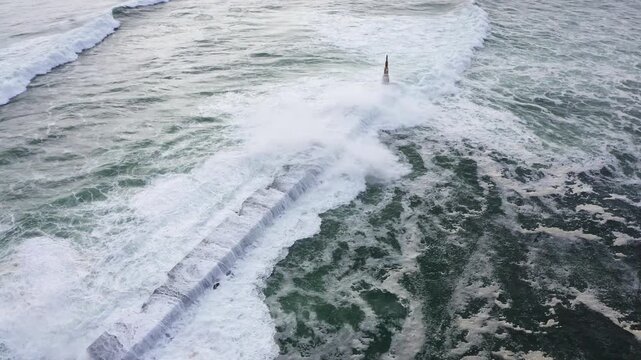 Huge waves crashing over Breakwater during winter storm Atlantic waves washing the lighthouse on Praia da Aguda sandy beach at Aguda settlement near Porto, Portugal. Incredible 4K flying drone video.