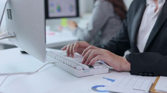 Professional businessman analyzing financial charts, typing on keyboard while working at modern office desk, engaging with digital technology and business data - Powered by Adobe