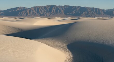 Panoramic vista of radiant gypsum dunes merging into distant hazy mountain ranges under a pristine