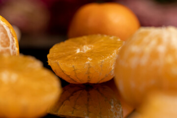 peeled tangerines close up, ripe orange tangerine is reflected on the black mirror surface