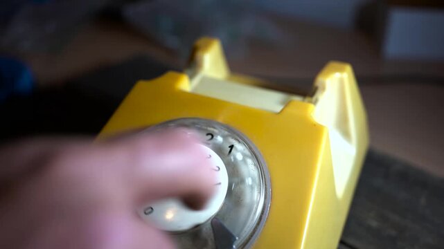 Man dialing 112 on old , aged , vintage rotary telephone fabricated in the 1980's.