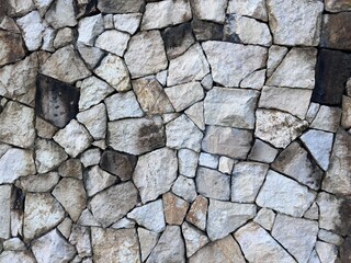 Old rough stone wall texture background with various stone sizes, ideal for rustic design or rustic wall background.