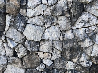 Old rough stone wall texture background with various stone sizes, ideal for rustic design or rustic wall background.