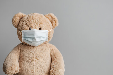 Teddy bear wears a medical face mask. Soft plush toy demonstrates protective measures. Cute and cuddly awareness.
