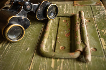 Military binoculars on a wooden box.Army binoculars on a green background.