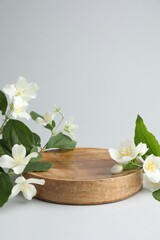 Fototapeta premium Beautiful jasmine flowers with leaves on light background. Space for text