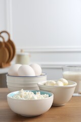 Different dairy products and eggs on wooden table indoors. Space for text