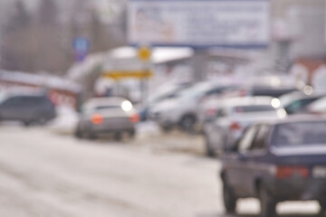 Blurred winter street scene with cars and snow covered landscape in urban setting.