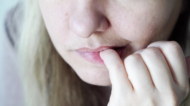 Caucasian young woman biting nails in nervous habit closeup sequence highlighting anxiety and stress.