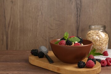 Tasty yogurt with granola and berries in bowl on wooden table, closeup. Space for text