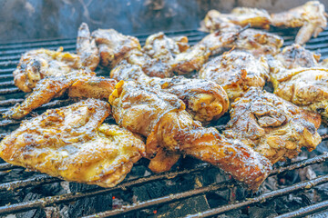 Grilled chicken roasting over hot coals. Juicy meat browning with smoke and fire in an outdoor setting. A traditional meal, perfect for family gatherings and weekend occasions.
