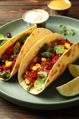 Tasty vegetarian tacos served with sauces on wooden table, closeup