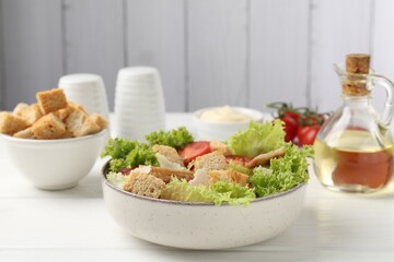 Delicious salad with croutons and ingredients on white wooden table, closeup