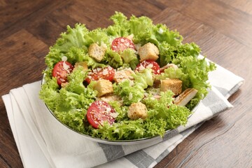 Tasty salad with croutons, tomatoes, cheese and chicken on wooden table, closeup