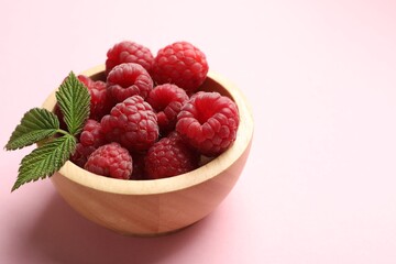 Tasty fresh ripe raspberries and leaves on pink background, closeup. Space for text