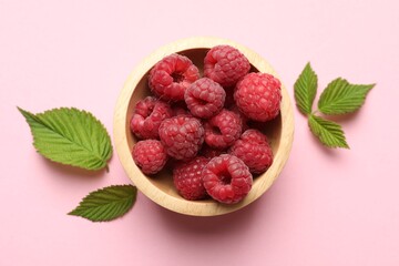 Tasty fresh ripe raspberries and leaves on pink background, flat lay