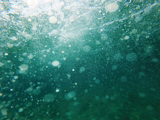 Underwater view with air bubbles and sunlight filtering through the sea in Halkidiki, Greece.