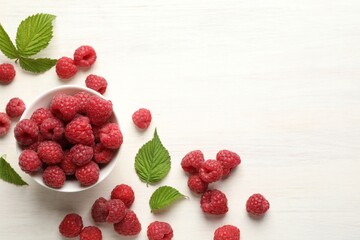 Tasty fresh ripe raspberries and leaves on white wooden table, flat lay. Space for text
