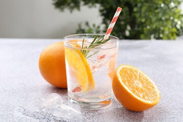 Refreshing soda water with orange slices and rosemary on grey table, closeup
