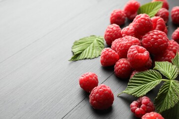 Tasty fresh ripe raspberries and leaves on black table, closeup. Space for text