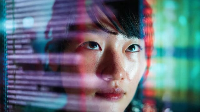 A person's face is illuminated by reflections of colorful lines of code and data representing a deep immersion in programming or cybersecurity