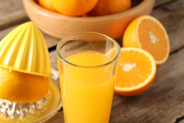 Tasty orange juice, fresh fruits and juicer on wooden table, closeup
