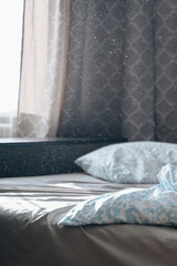 Unmade bed in morning sunlight with dust particles floating in warm, soft rays