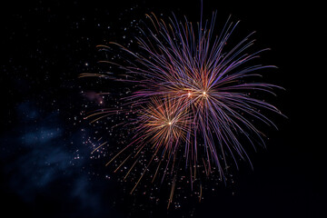 Fototapeta premium Single firework explosion in the clean sky with copy space for text. Isolated on blue and night background. Colorful and bright fireworks