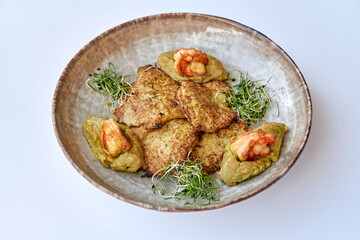 A Mouthwatering Plate of Crispy Vegetable Fritters Topped with Fresh Shrimp and Garnished with Microgreens on a Stylish Ceramic Dish