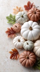Autumn pumpkins in varied sizes and colors arranged with vibrant leaves on a beige backdrop provide an ideal setting for text
