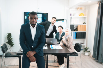 Frustrated African American businessman stressed and overwhelmed in meeting room after facing business problems with diverse team, business failure, corporate pressure, financial difficulties.