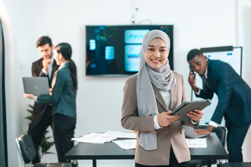 Confident Muslim businesswoman smiling and giving thumbs up while holding a tablet during a successful team meeting in a modern office environment showing leadership diversity and achievement
