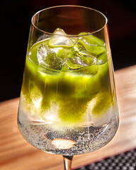 Sparkling matcha cocktail garnished with ice cubes in elegant glassware