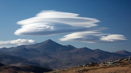 Spectacular lenticular clouds hovering over majestic mountain peaks under a clear blue sky