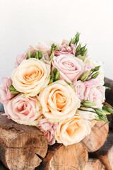 Wedding rings resting on beautiful peach and pink rose bouquet on rustic wood
