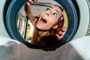 Woman looking surprised inside washing machine drum