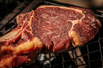 A thick-cut raw tomahawk steak rests on a hot metal grill, showcasing rich marbling and a long bone handle. Ideal for barbecue or steakhouse-style cooking.